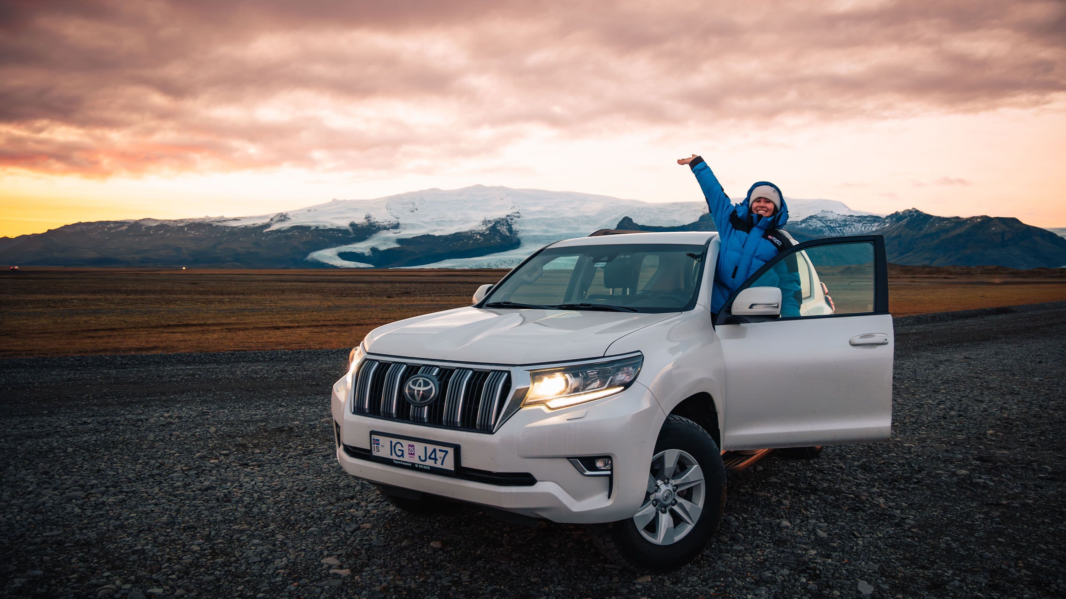 Image of a person standing in the door frame of an automatic toyota landcruiser in Iceland